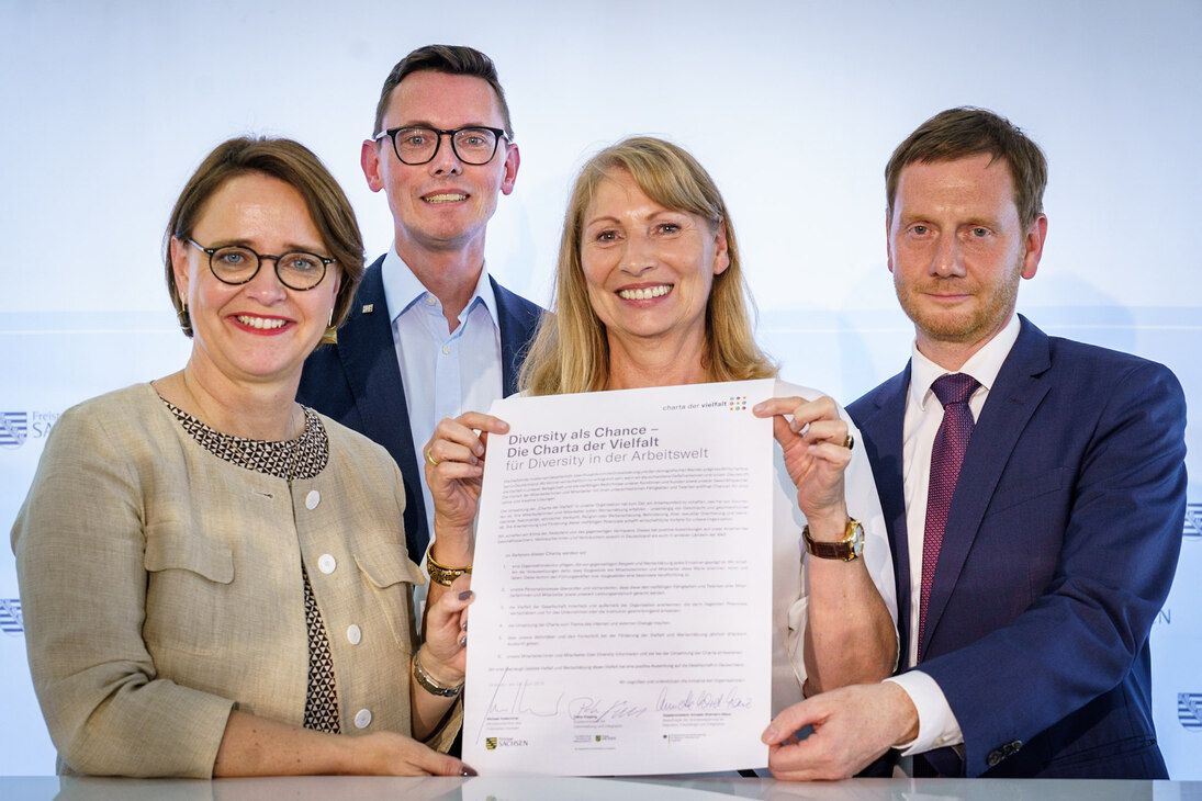 Staatsministerin Petra Köpping, Staatsministerin Annette Widmann-Mauz und Ministerpräsident Michael Kretschmer halten die soeben unterzeichnete Charta der Vielfalt in den Händen.