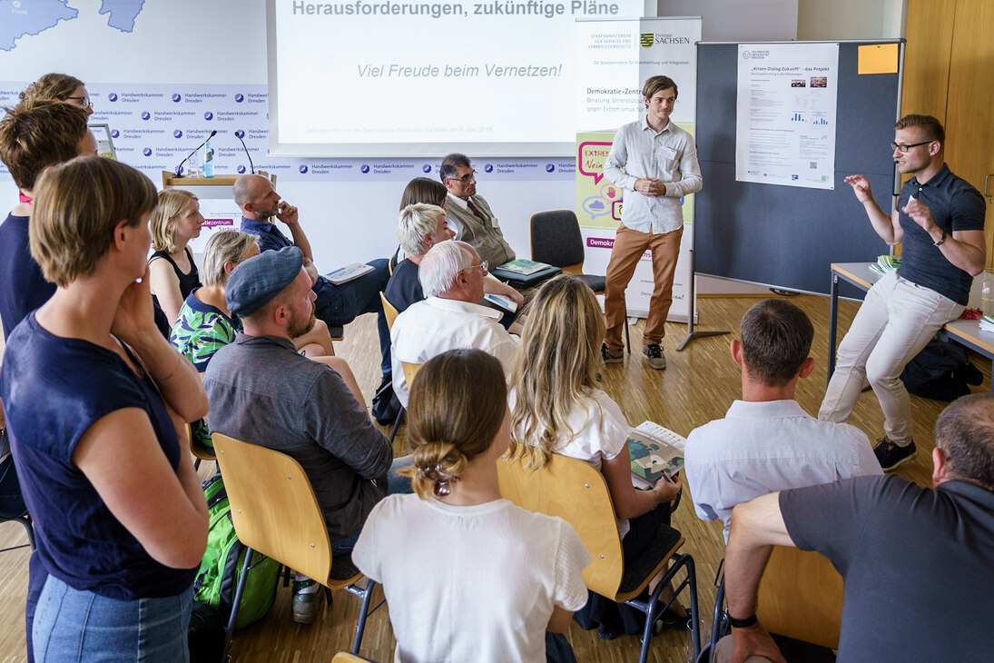 Ein Bild vom Workshop Krisenkommunikation mit den zwei Referenten und dem Publikum.