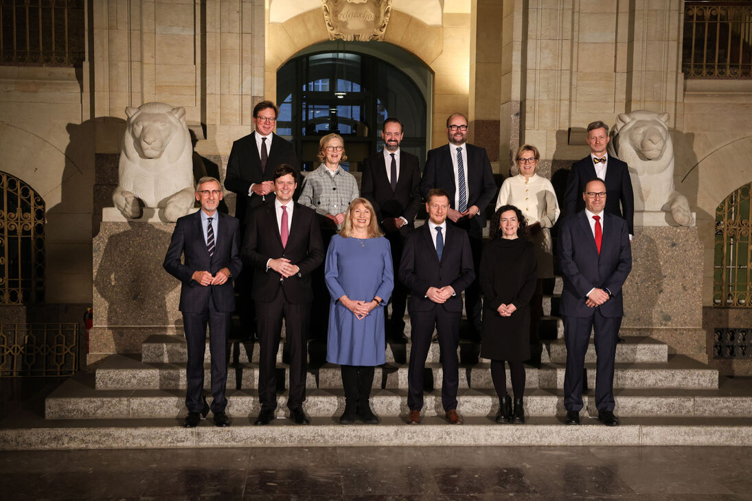 Alle Minister stehen auf einer Treppe in zwei Reihen und lächeln in die Kamera