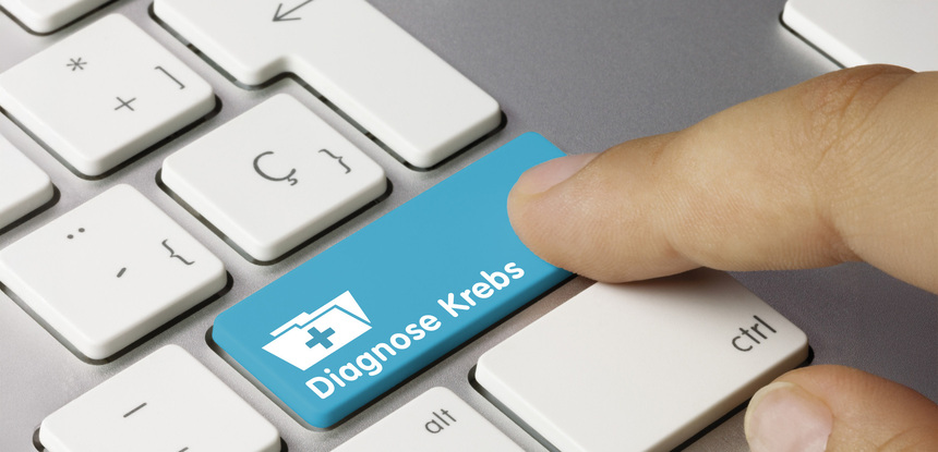 Bild zeigt eine Computertastatur, wo ein Finger auf die Taste "Diagnose Krebs" klicken will