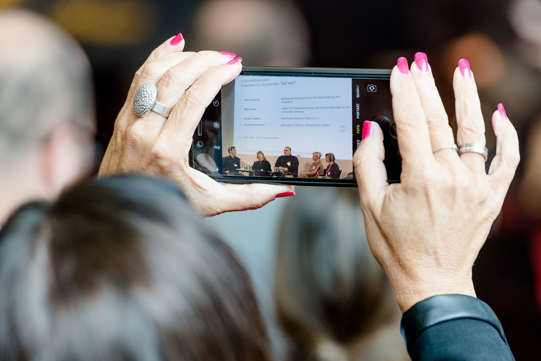 Eine Teilnehmerin fotografiert die Diskussionsrunde beim KORA-Forum