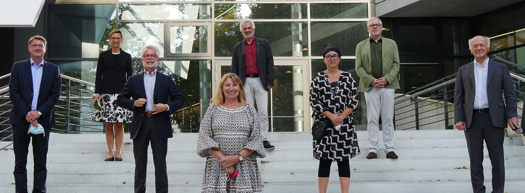 Gruppenfoto auf Treppenstufen vor einem verglasten Gebäudeeingang