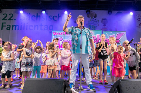 Der Künstler Volker Rosin singt auf der Bühne des Familientages zusammen mit vielen Kindern