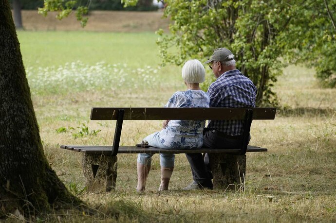 Zwei Senioren sitzen auf einer Parkbank 