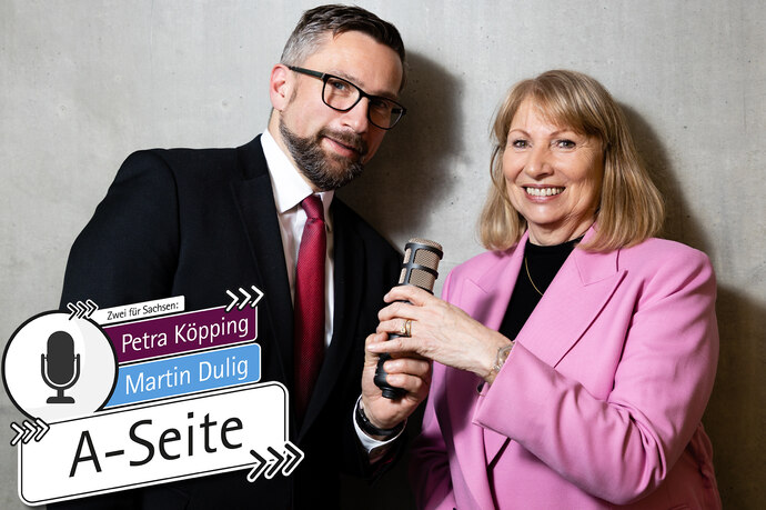 Martin Dulig und Petra Köpping stehen nebeneinander und halten Mikrofon hoch