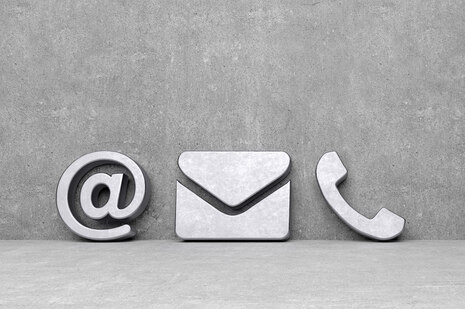 Steinwand. Davor stehen Symbole für Internet, Email und Telefon
