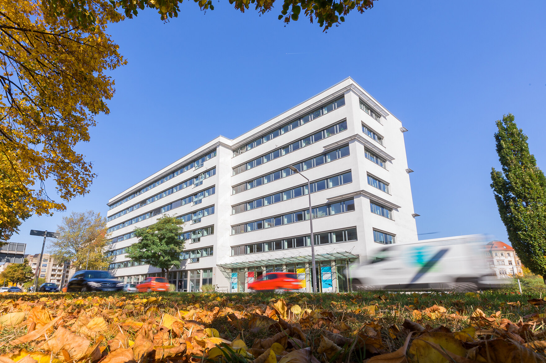 Ein weißes langes Bürogebäude steht an einer Straße. Es ist das Sozialministerium